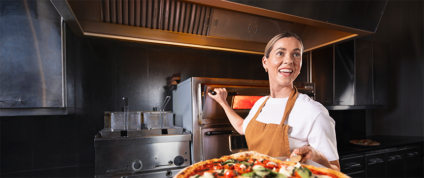 Dame som tar ut pizza av ovnen